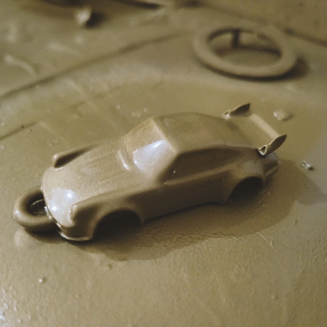 Beige resin cast of a sports car keychain prototype on a casting surface